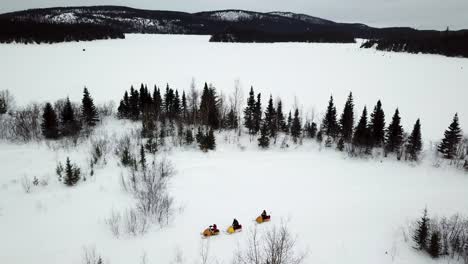 Imagen-Aérea-De-Un-Rally-De-Motos-De-Nieve-En-Un-Lago-Y-En-El-Bosque-En-Chibougamau,-Quebec