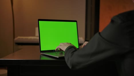 hombre escribiendo en el teclado de la computadora portátil con pantalla verde, rápido dolly en el tiro