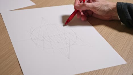 female hand indicating with the pencil the features of a geometric drawing made on a sheet of paper