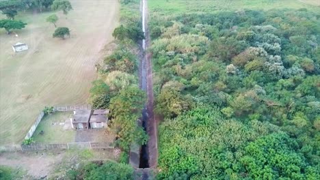 drone-flying-over-a-canal-with-sewerage-water-heading-up-to-a-squatter-camp-with-shacks