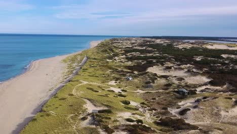 Luftflug-über-Den-Strand-Des-Damms-über-Goldenen-Sand-Und-Strahlend-Blaues-Wasser