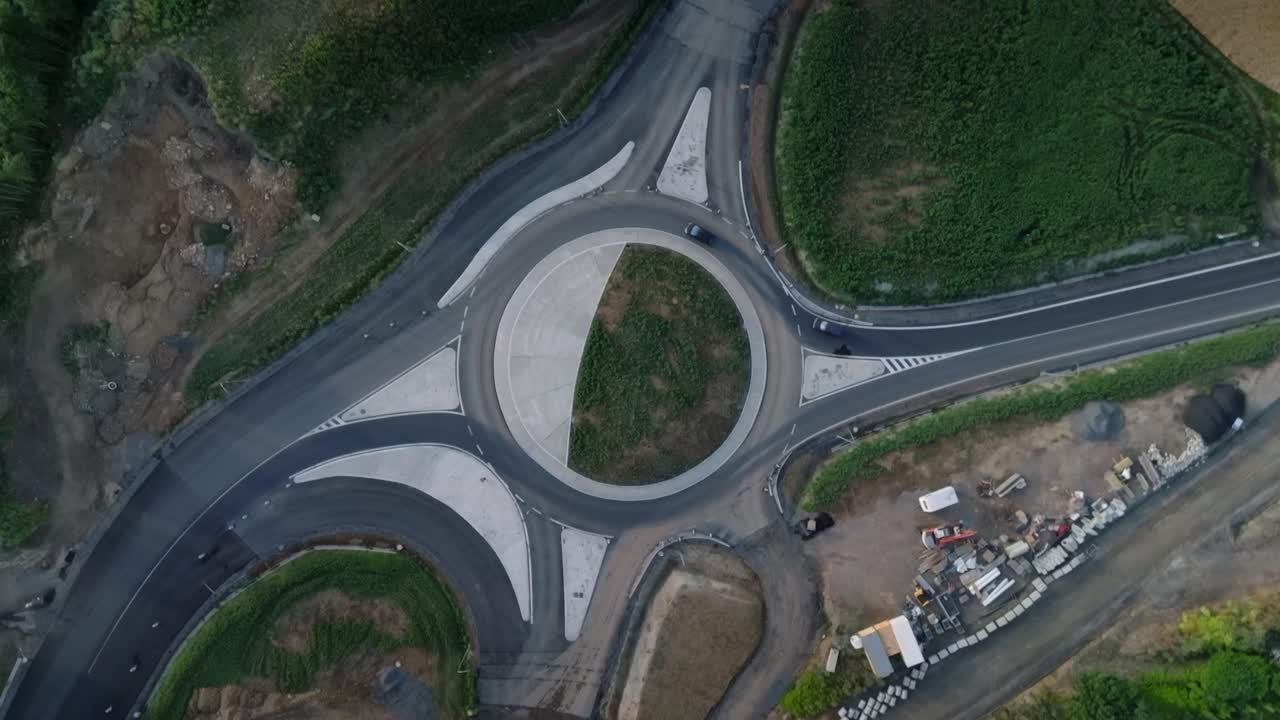 Top down bird's eye view of the roundabout through which cars pass