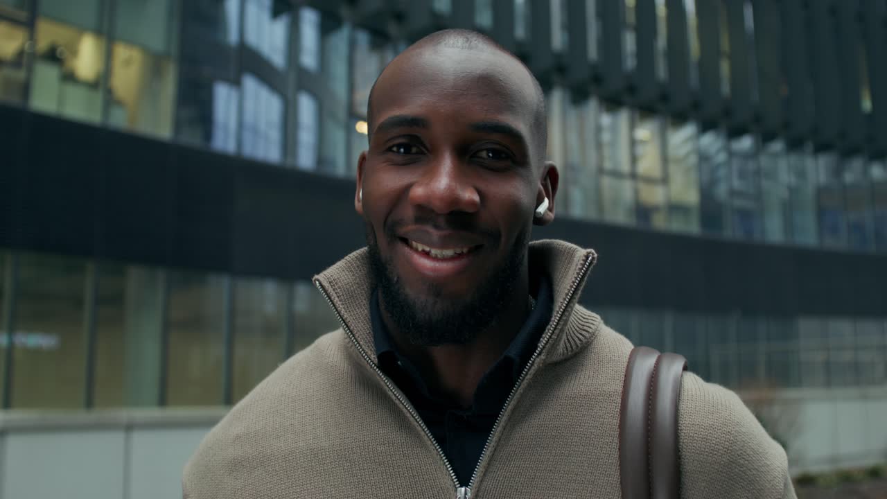 hombre sonriente frente a un edificio de oficinas moderno