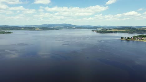 a-cinematic-view-from-a-drone-that-rotates-over-a-large-blue-lake-and-offers-a-view-of-the-landscape