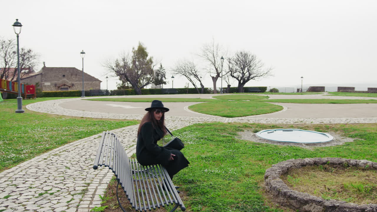 Elegant Woman Arriving At The Green Park And Sitting On The Bench