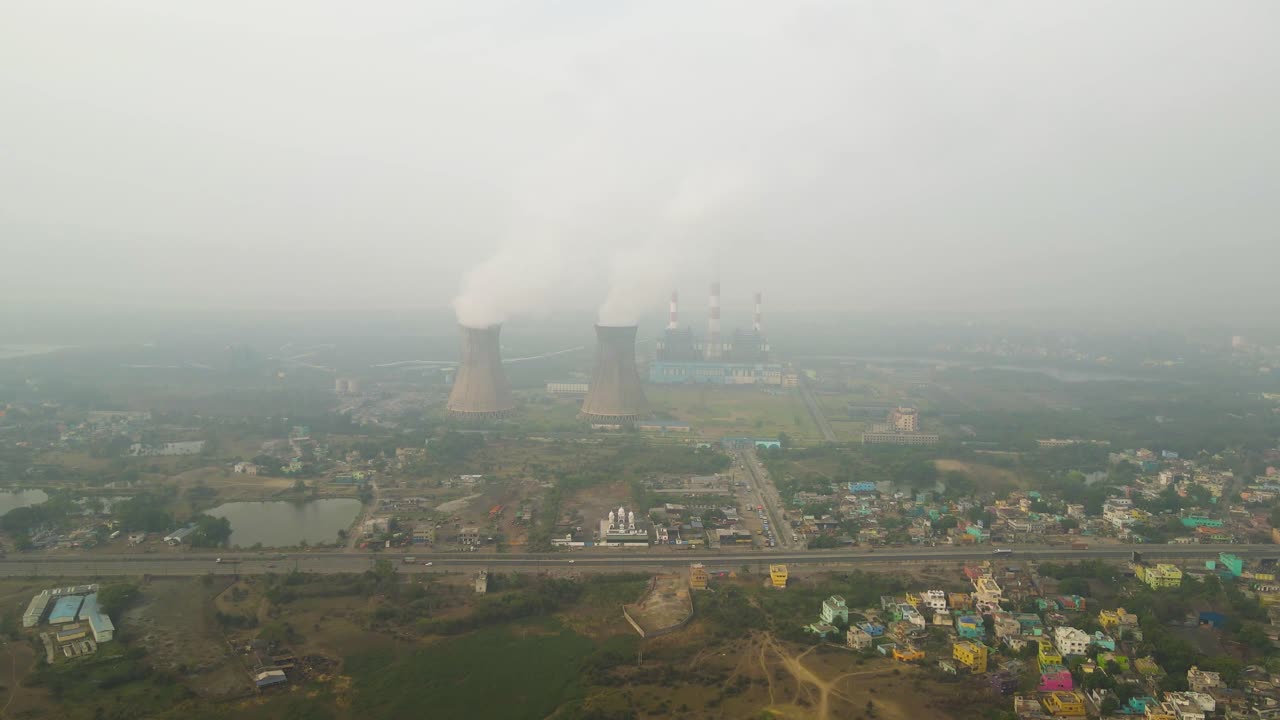 Aerial drone shot of factories in India, showing pollution from chimneys against an industrial landscape.