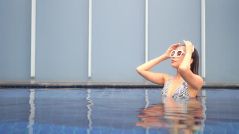 a lovely woman in a zebra print bathing suit smoothes her wet hair from her face