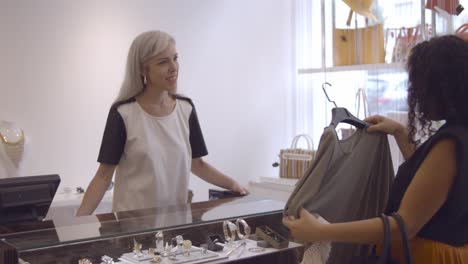 serious latin woman buying clothes in fashion store