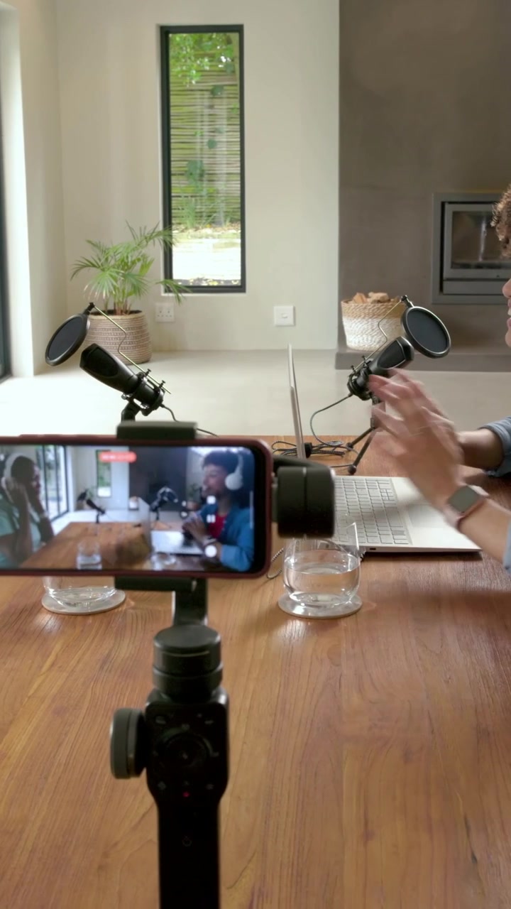 Vertikales Video: Moderatoren mit weißen Headsets überprüfen ihre Mikrofone für eine Podcast-Aufnahme per Telefon zu Hause.