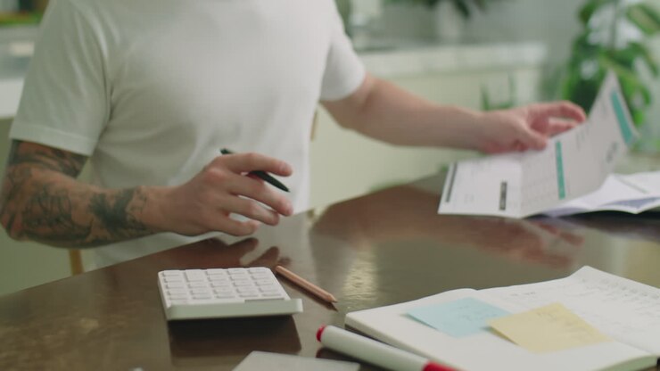 Uomo che conta le proprie finanze personali con una calcolatrice a casa