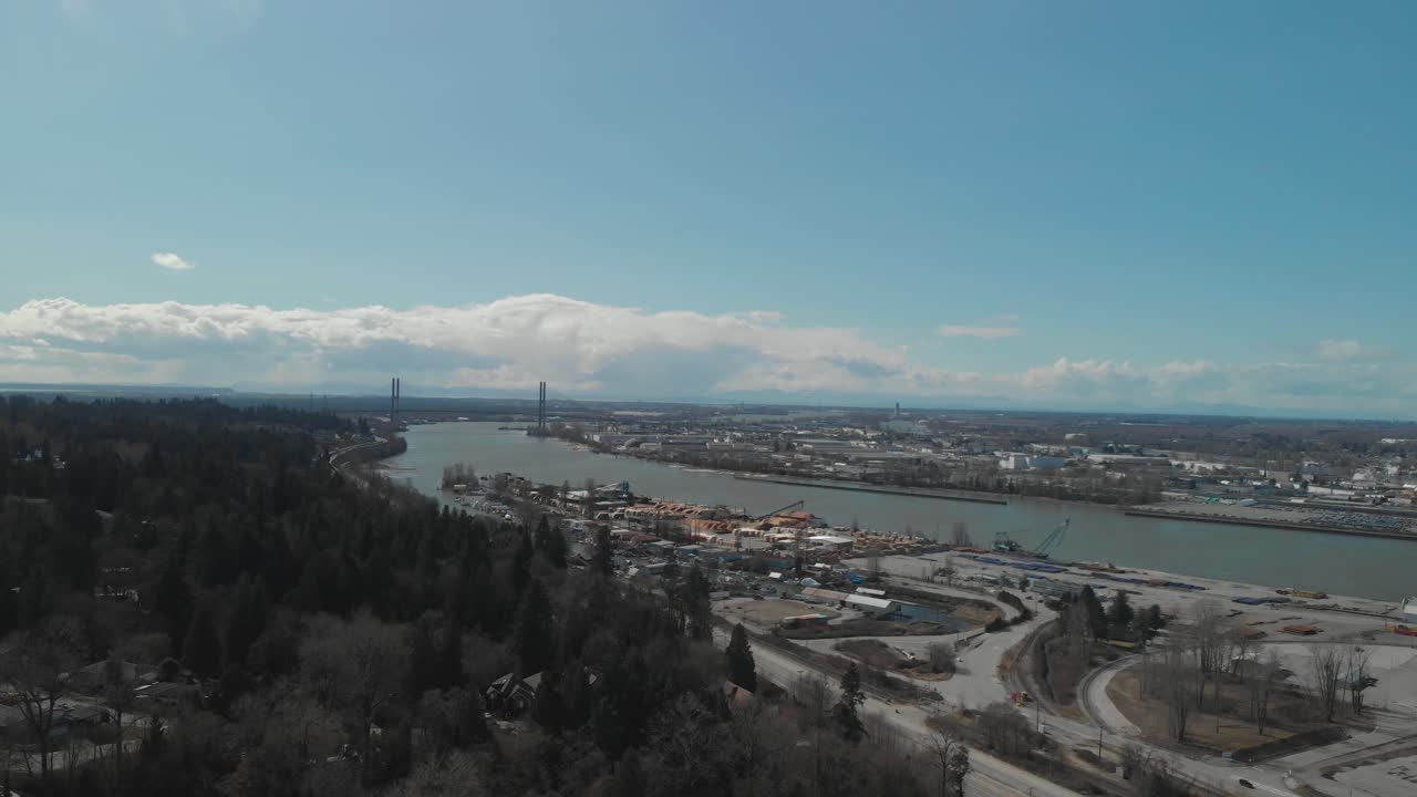 vista panorámica del delta bc en el borde del río fraser con el puente alex fraser en el fondo día brillante cielo azul nubes aérea amplia marcha atrás revelador vecindario próxima carretera