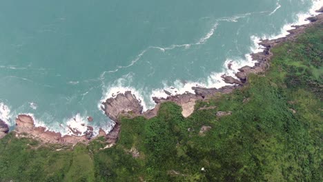 aerial view of a jagged rock island, surrounded with lush green nature and hong kong bay water