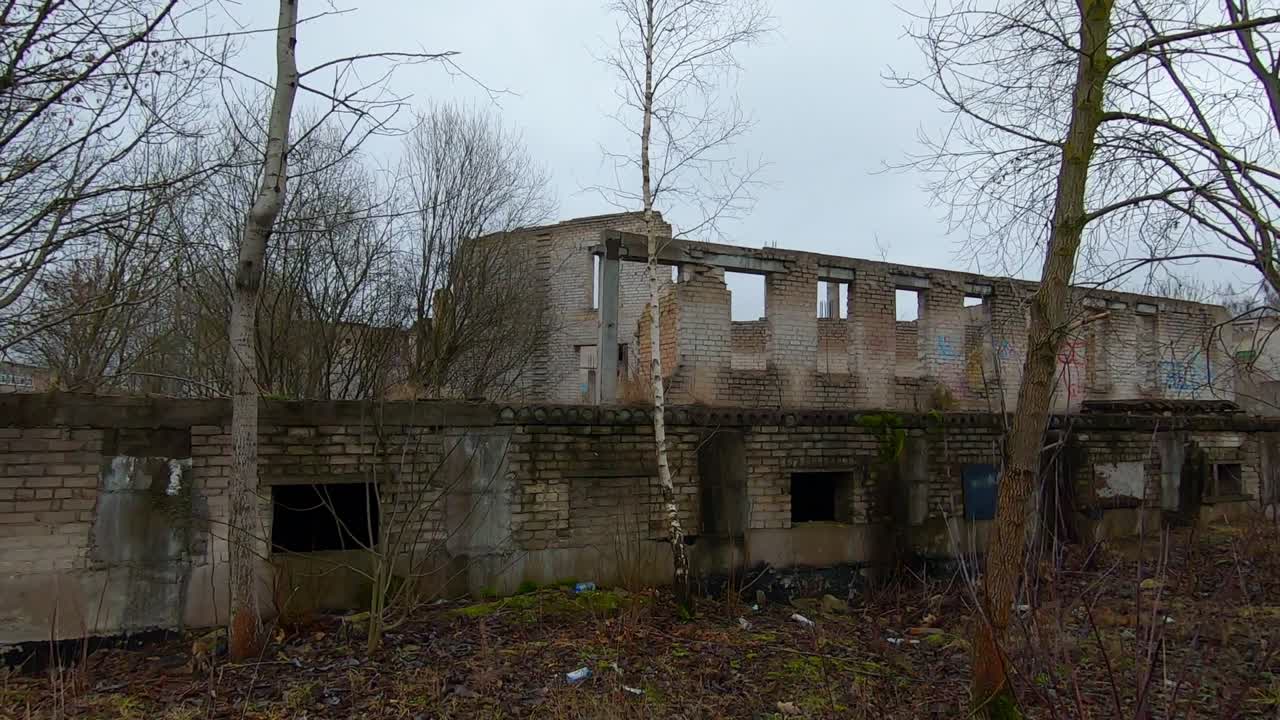 Abandoned White Brick Building Between Trees And Shrubs. Dolly Out Slow Motion Shot