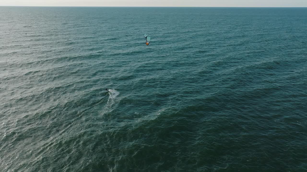 establecimiento de una vista aérea de un grupo de personas dedicadas al kitesurf, día soleado de verano, olas altas, deportes extremos, playa de karosta en el mar báltico, amplia toma de un dron birdseye moviéndose hacia adelante