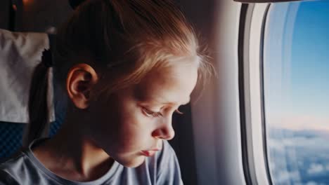 montage of a young girl looking out the window of an airplane, her expressions changing from curiosity to contemplation as she takes in the view