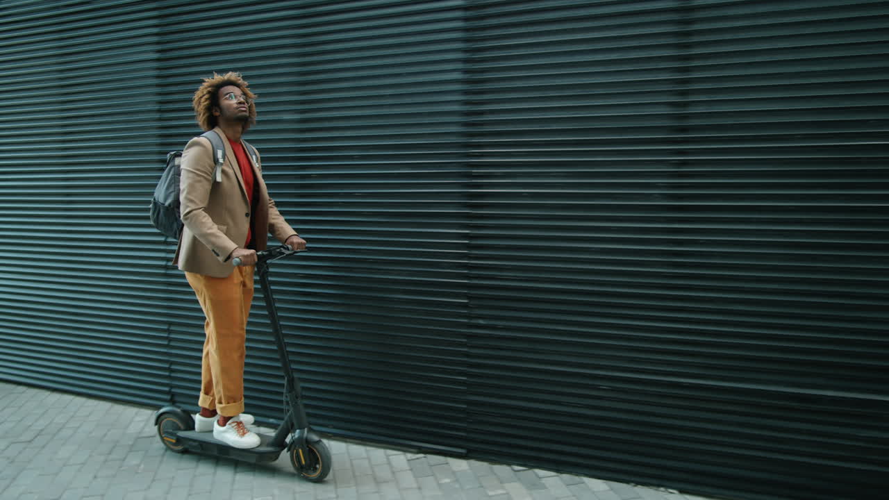 Young Black Man Riding E-Scooter in City