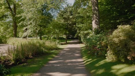 Gravel-Path-at-Annelunds-Park-at-Summer-Time-in-Borås-Sweden,-Wide-Shot-Tracking-Forward