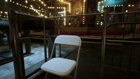 a white folding chair in front of a closed carnival carousel