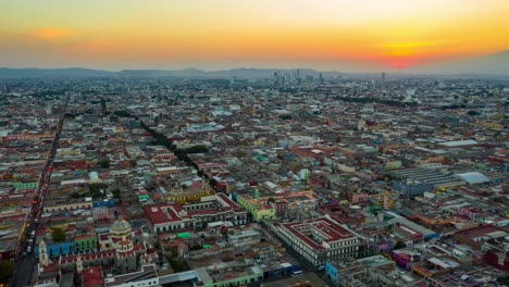 Leuchtend-Orangefarbener-Sonnenuntergang-über-Puebla-City,-Mexiko,-Luft-hyperlapse-rückzug