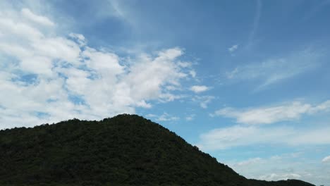 在日落前的下午,山上綠色的樹木放大了,揭示了雲和藍色的天空的 siluet