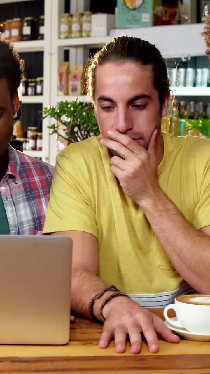 Group of friends using laptop while having cup of coffee