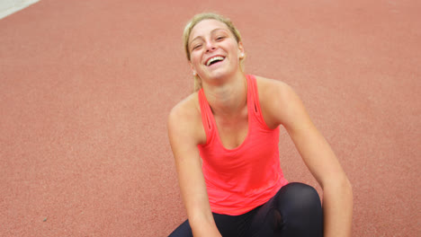 Front-view-of-Caucasian-female-athlete-tying-shoelace-on-running-track-4k