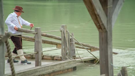 a slow motion of a man guiding the wooden raft on the drava river