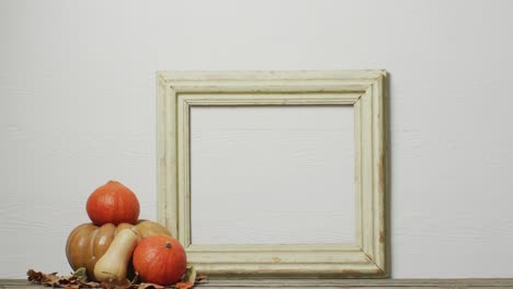 Video-of-pumpkins-with-autumn-leaves-and-frame-with-copy-space-on-white-background