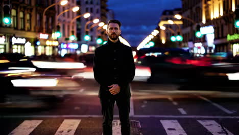Man standing on a crosswalk at night in a city