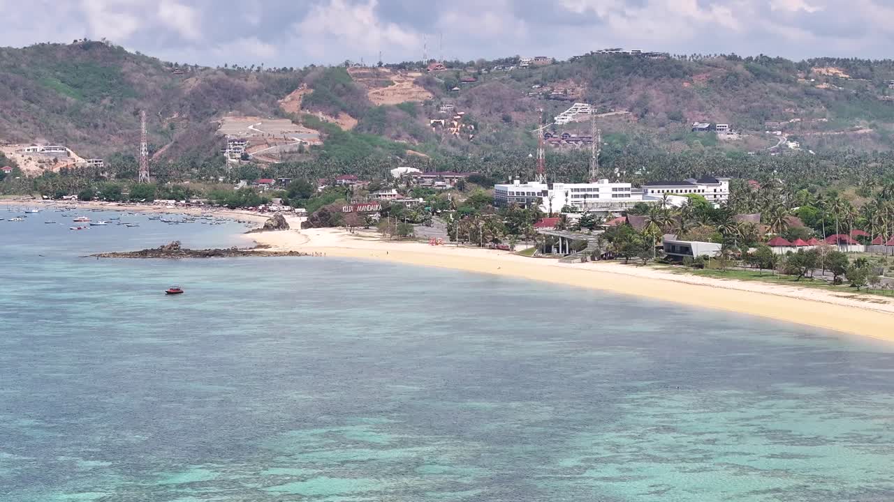 Kuta Beach in Lombok Island, Indonesia. Aerial crane reveal settlement, resorts and lang sand beach.