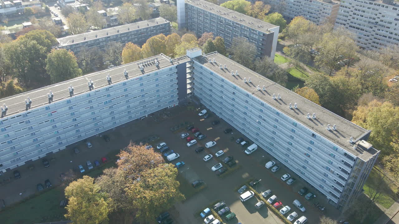Jib down of social housing flat with busy parking lot in autumn