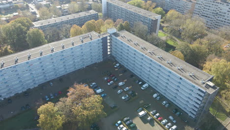 jib down of social housing flat with busy parking lot in autumn