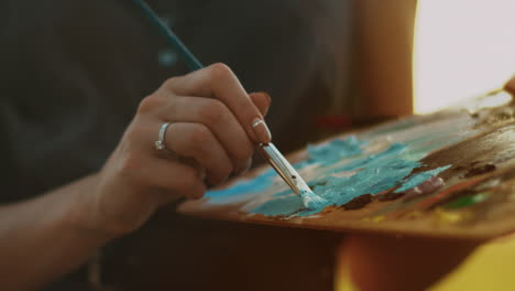 female artist holding dirty palette with paints. woman hand holding brush