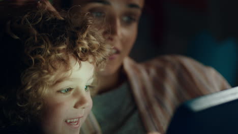niño feliz usando una computadora tablet con su madre enseñando a su hijo jugando juegos en la tecnología de pantalla táctil divirtiéndose antes de acostarse