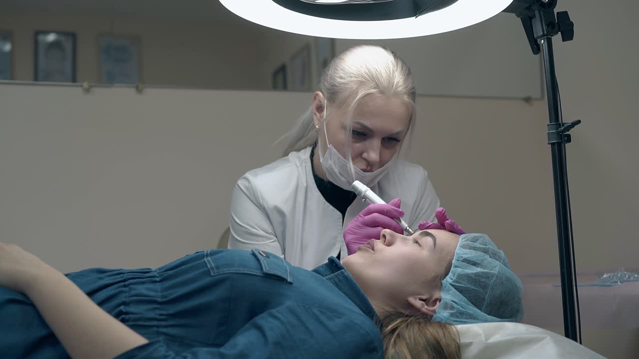 cosmetologist applies permanent eyebrow in beauty salon