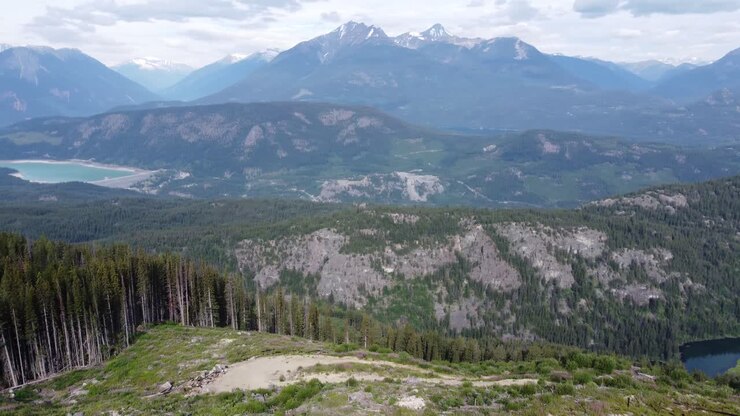 Paesaggio montano innevato con diga idroelettrica che genera elettricità pulita con fiume e alberi, Canada BC, ripreso con drone aereo in 4K