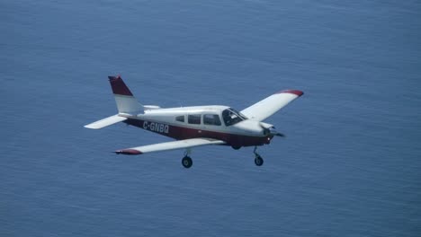 single engine propeller aircraft flying above the sea, air to air view