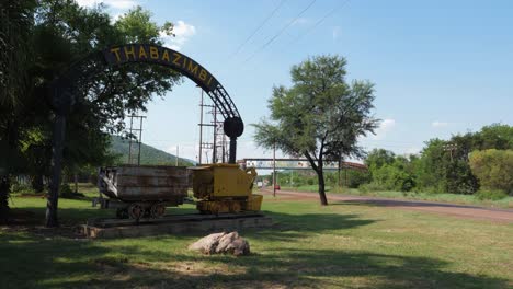 Cartel-De-Bienvenida-En-Thabazimbi,-Sudáfrica-Muestra-Viejos-Vagones-De-Mineral-De-Minería