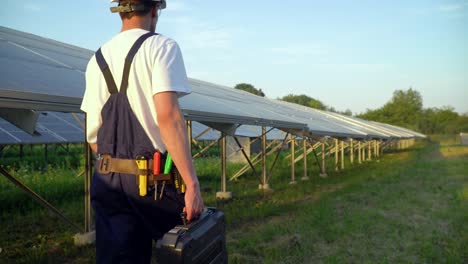 technician walking in solar cell farm through field of solar panels checking the panels at solar energy installation