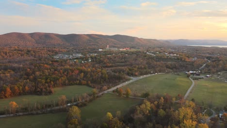 A-rural-river-valley-sunset-with-fields,-forests,-mountains,-rolling-hills,-cars,-roads,-and-a-river-in-the-background