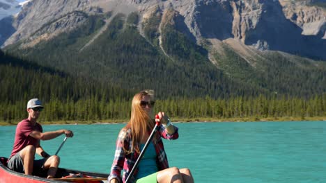 Front-view-of-young-couple-rowing-boat-on-a-turquoise-river-in-the-sunshine-4k