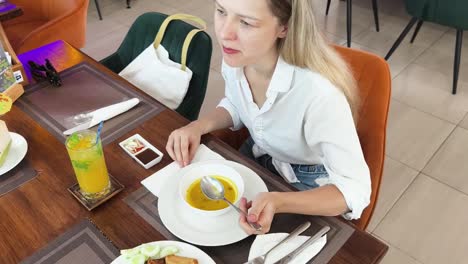 mujer comiendo sopa en un café