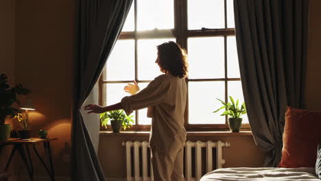 woman standing by the window in a cozy bedroom