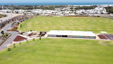 reveal shot of sports field, building, flood lights and beyond, aerial