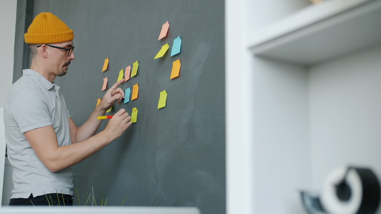 Person Brainstorming on a Wall with Sticky Notes