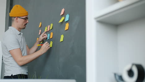 person brainstorming on a wall with sticky notes