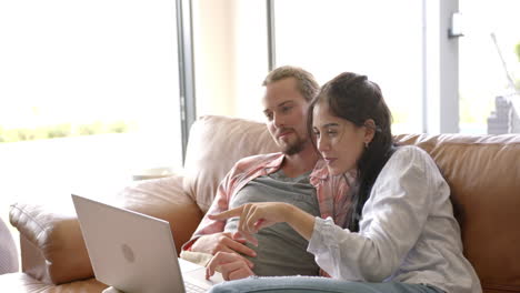 Una-Pareja-Birracial-Está-Usando-Una-Computadora-Portátil-En-Casa-En-El-Sofá