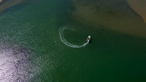 aerial of small boat cruising on beautiful and clear waters on a lagoon next to the ocean.