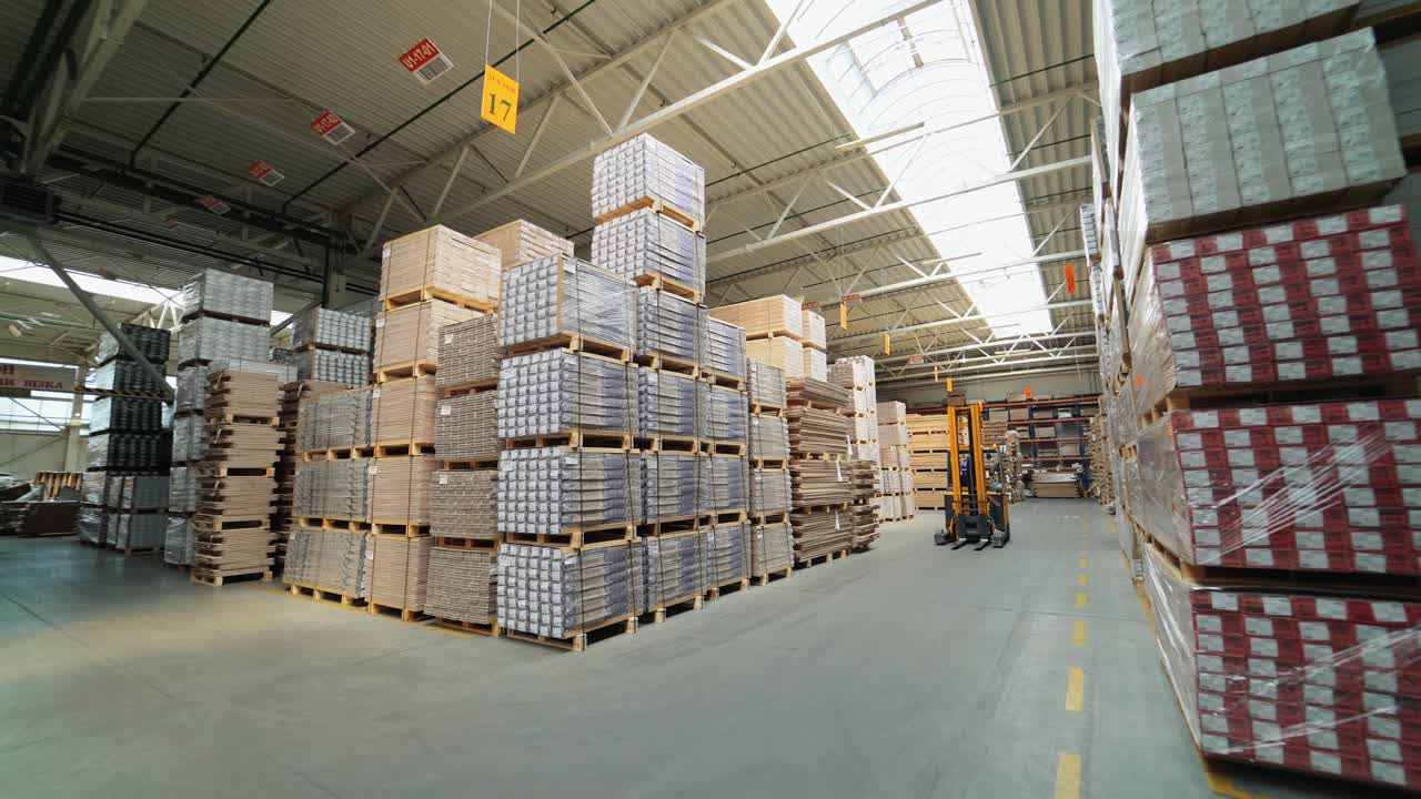 An electric self-propelled forklift rides in rows between the shelves with parquet in the stock. Warehouse of woodworking plant