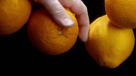 mano masculina con naranjas frescas bajo el agua.